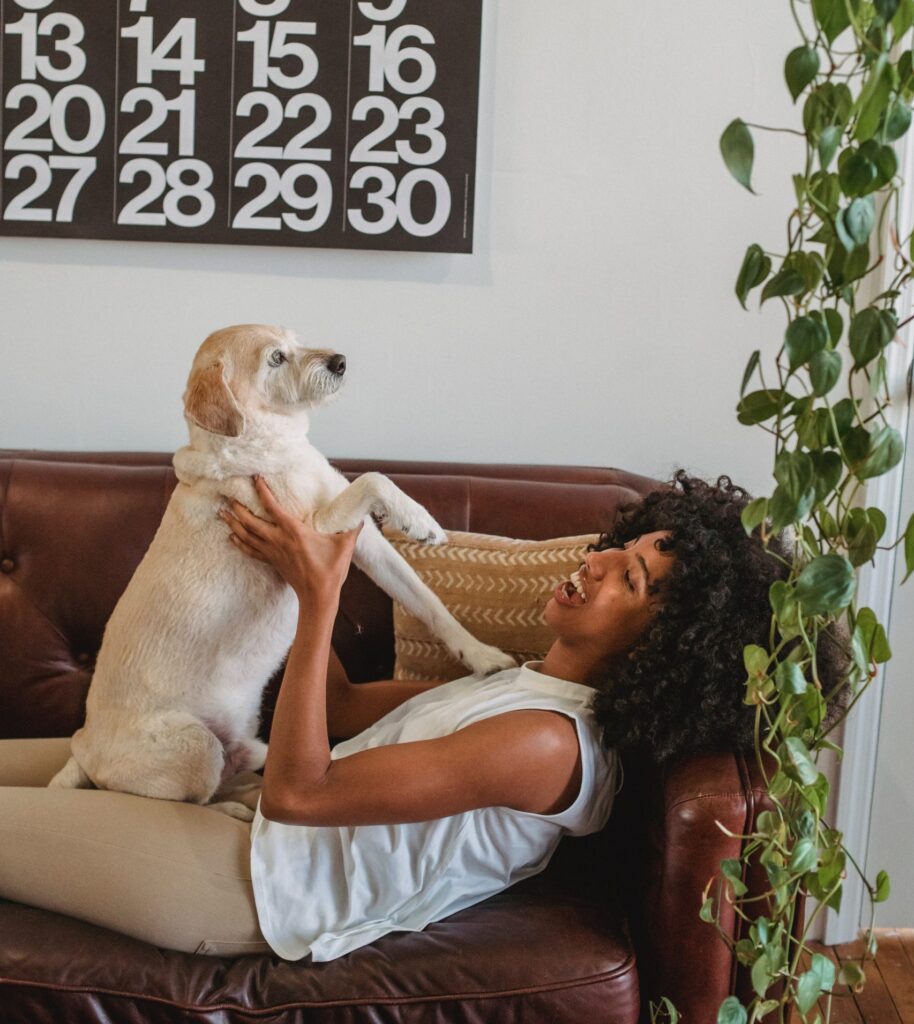 Cheerful woman laying on couch holding her dog
